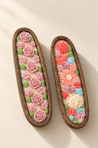 Two decorative wooden trays holding colorful floral resin art. The tray on the left features pink roses and small pink blossoms with green leaves on a white background.