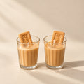 Two glasses with Biscoff cookie candles on a gray background