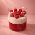 Layered dessert with red and white components in a glass on a pink background